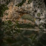 gray rocky mountain beside body of water during daytime